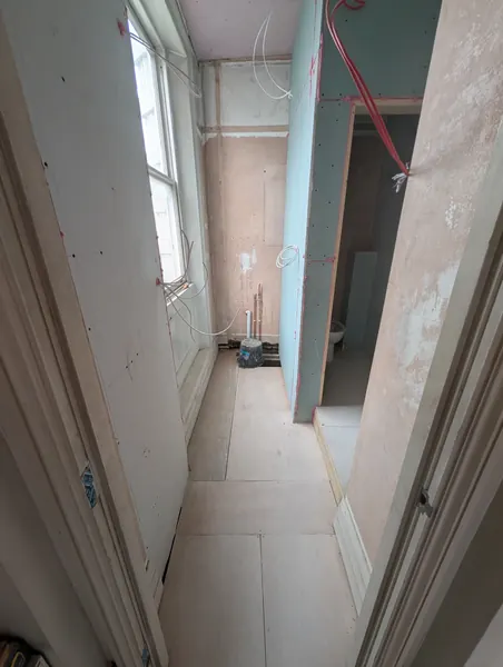 A corridor of new boarded partitions beside a tall sash window