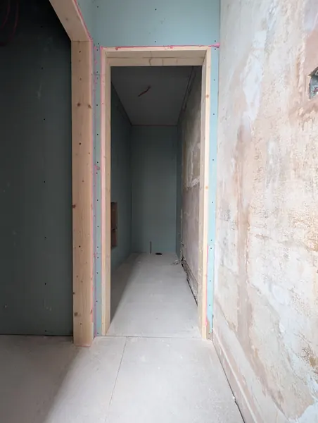 A new timber-framed doorway in a boarded partition, leading into a small room