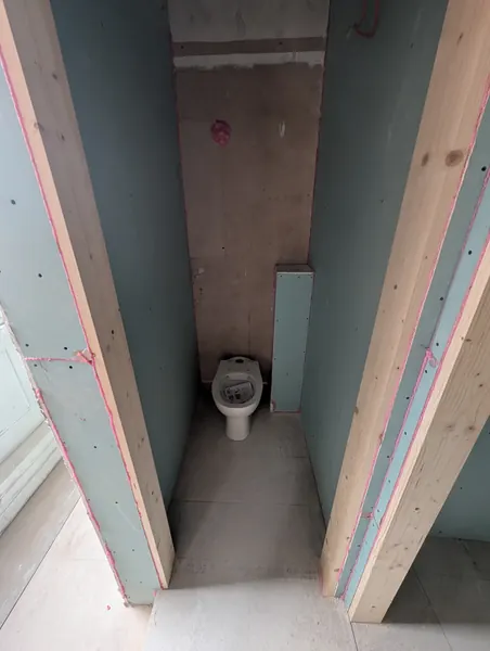 A toilet in a small room lined with new boards