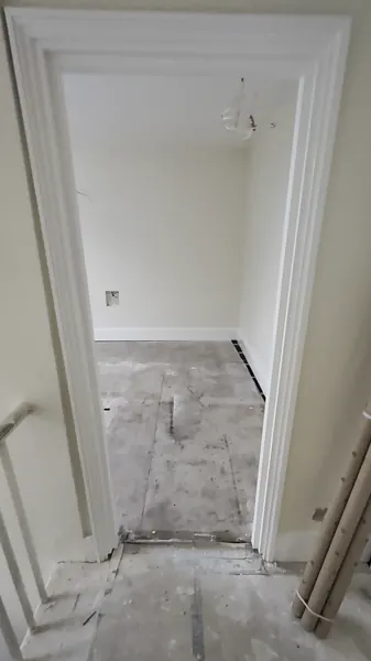 Looking through a painted door frame from the landing into a freshly painted room, with the stair handrail on the left