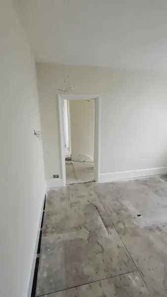 A freshly painted room with white skirting, looking towards a doorway