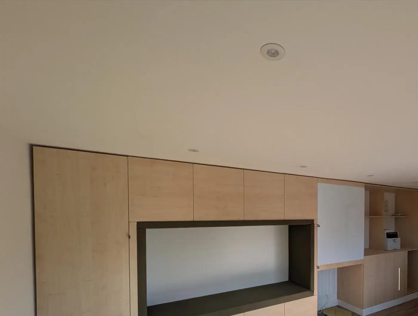 Bespoke birch-ply joinery wall with a recessed display niche in a completed commercial fit-out