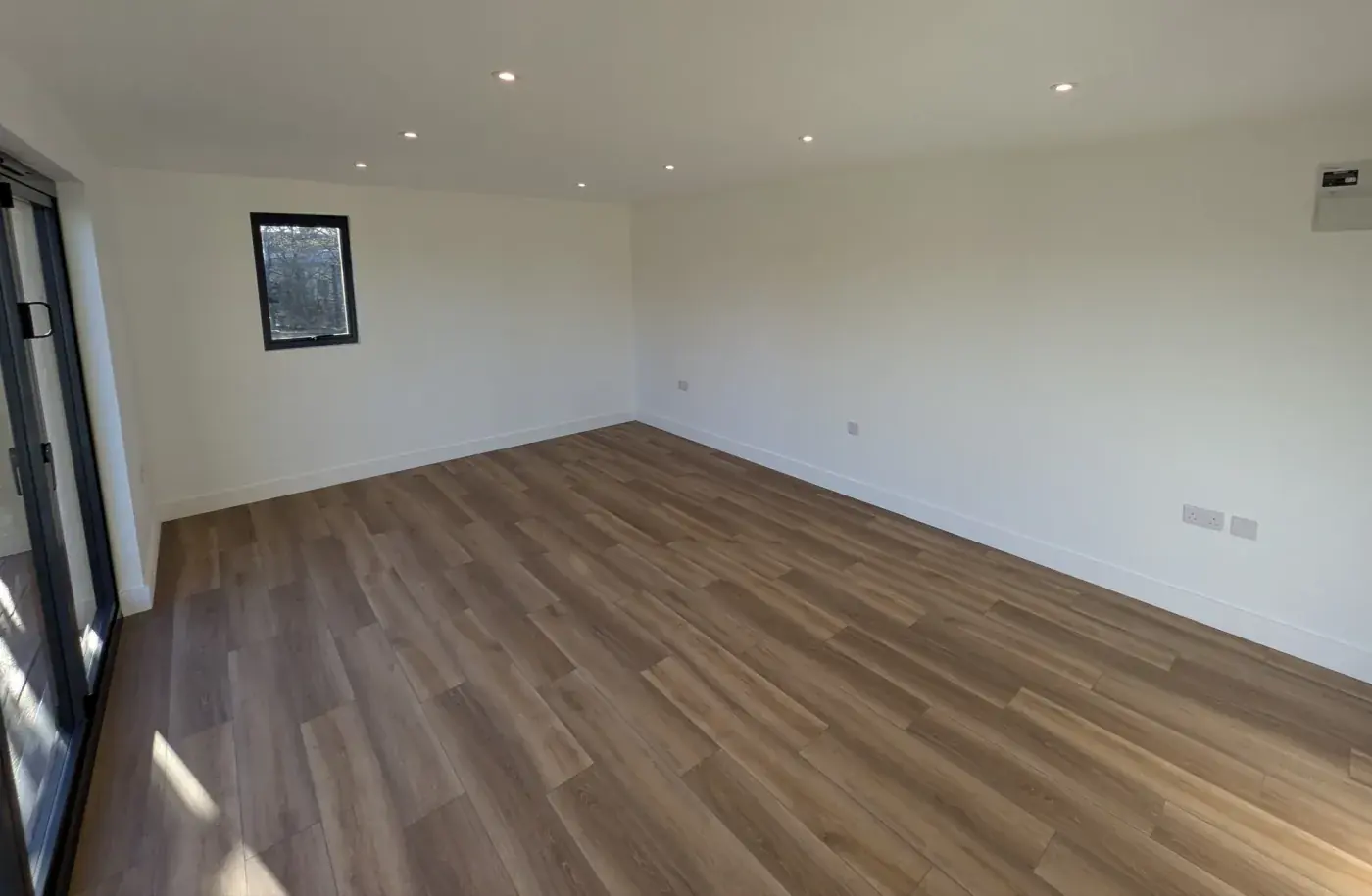 A newly finished, empty extension interior with raking daylight across a wood floor