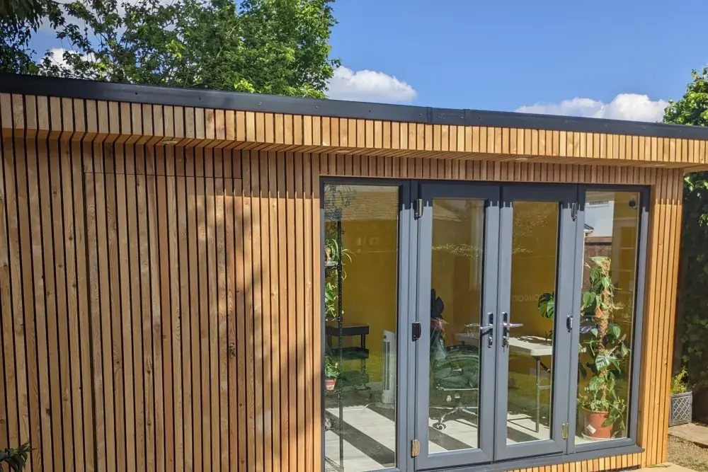 Close view of vertical cedar cladding meeting the glazing, lit by afternoon sun