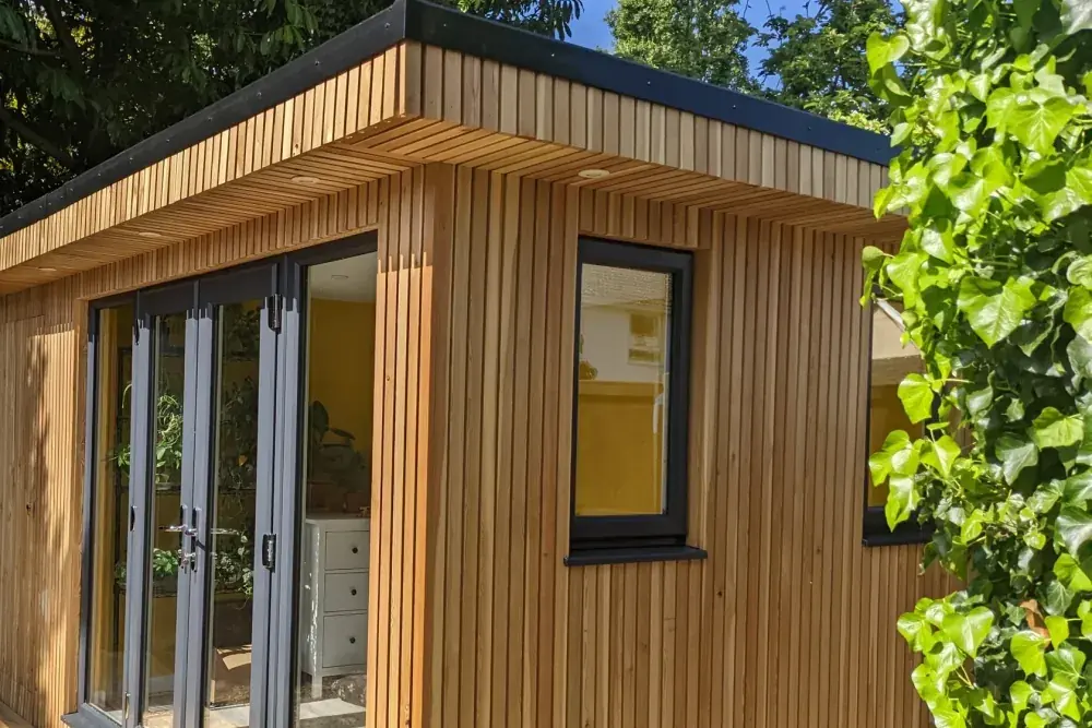 Corner detail of vertical cedar cladding meeting the roof edge of a garden room