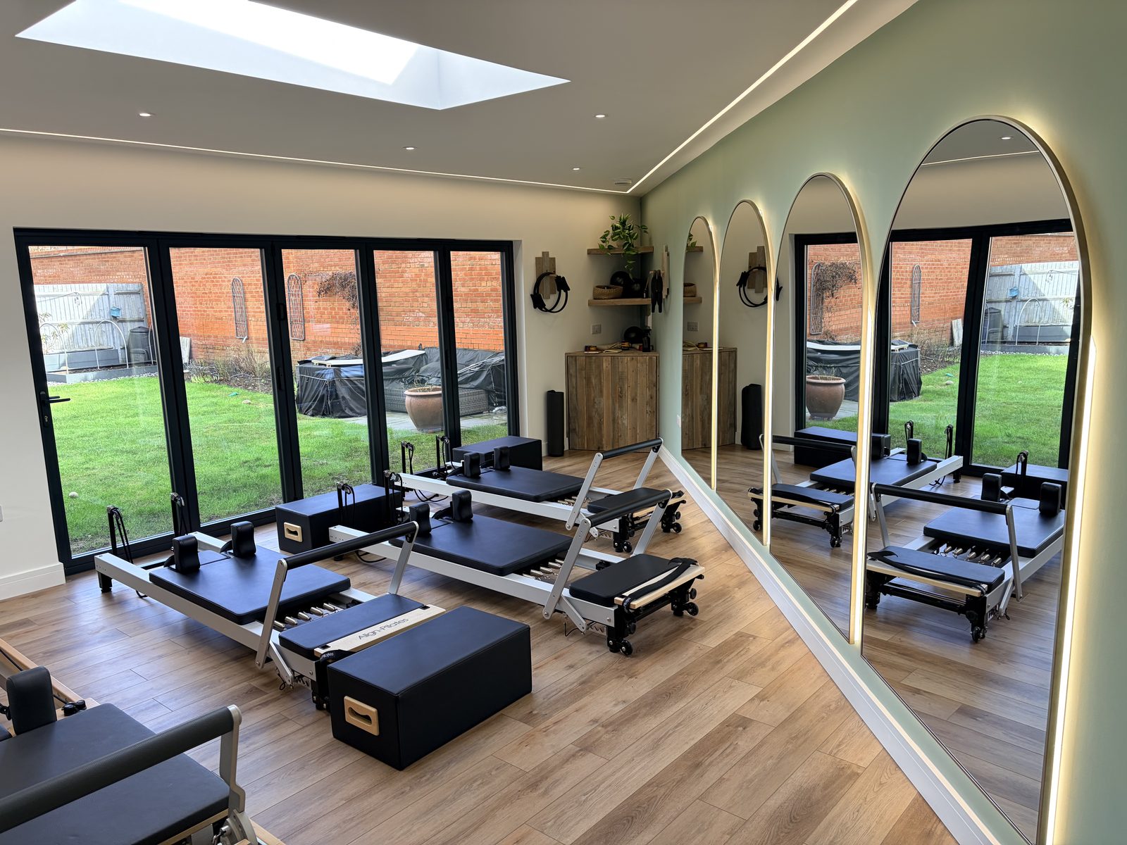 Inside a Pilates studio we built, with reformers, arched mirrors and bi-fold doors onto the lawn